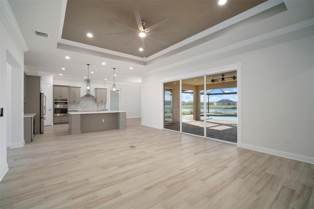 5325 San Remo Cir, Wimauma, FL 33598 - unfurnished living room featuring recessed lighting, light wood-style flooring, a tray ceiling, and ceiling fan