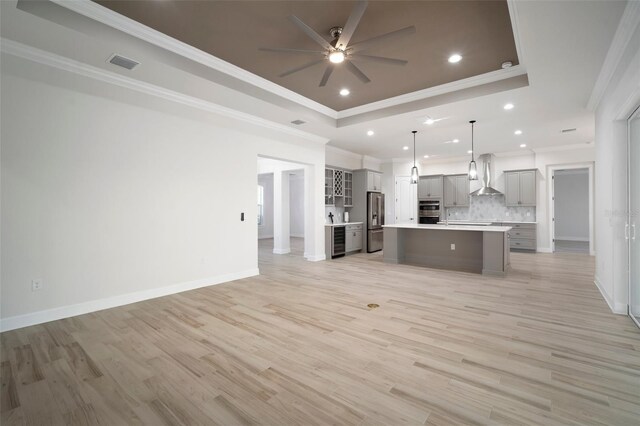 5325 San Remo Cir, Wimauma, FL 33598 - kitchen featuring a raised ceiling, wall chimney exhaust hood, stainless steel fridge, open floor plan, and gray cabinetry