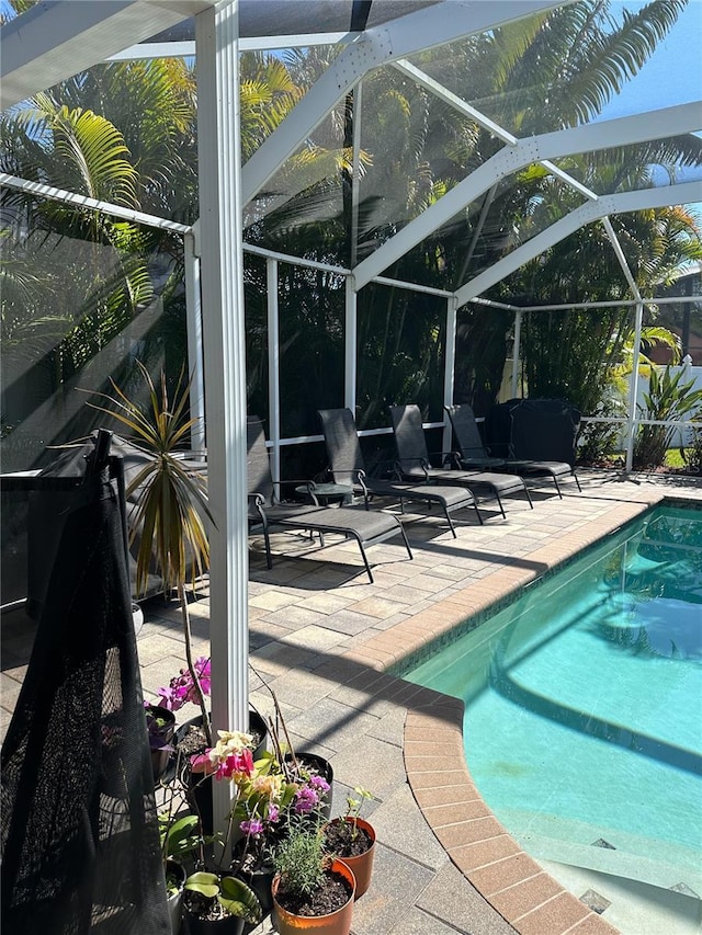 outdoor pool featuring glass enclosure and a patio area