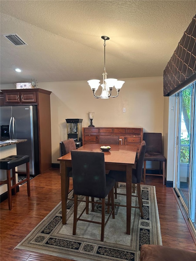 dining space with an inviting chandelier, visible vents, a textured ceiling, and dark wood-type flooring