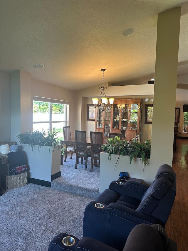 living room with a textured ceiling, vaulted ceiling, carpet floors, baseboards, and a notable chandelier