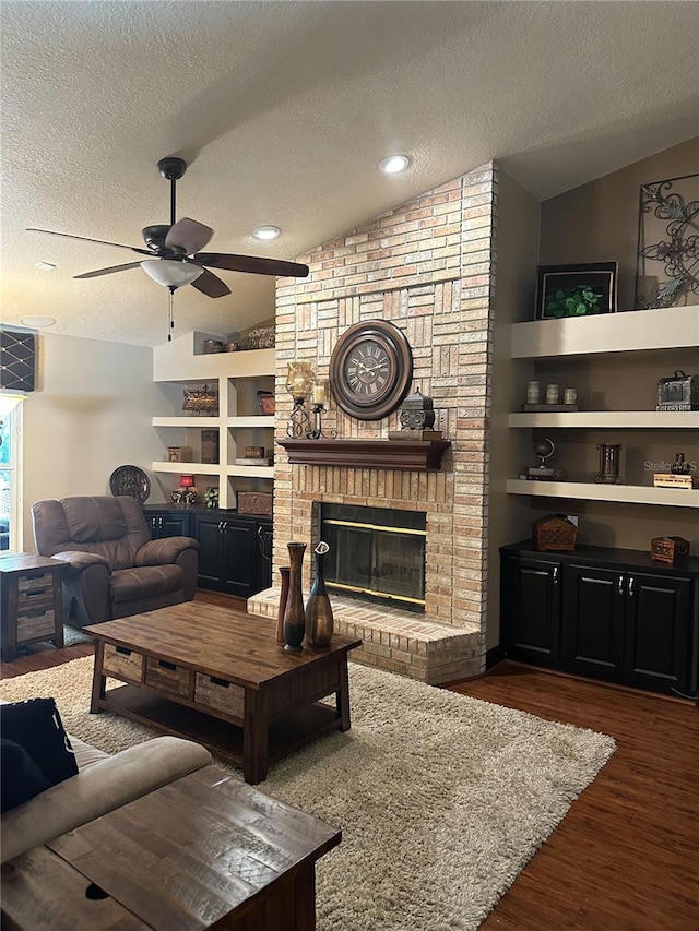 living area with a textured ceiling, ceiling fan, wood finished floors, and vaulted ceiling
