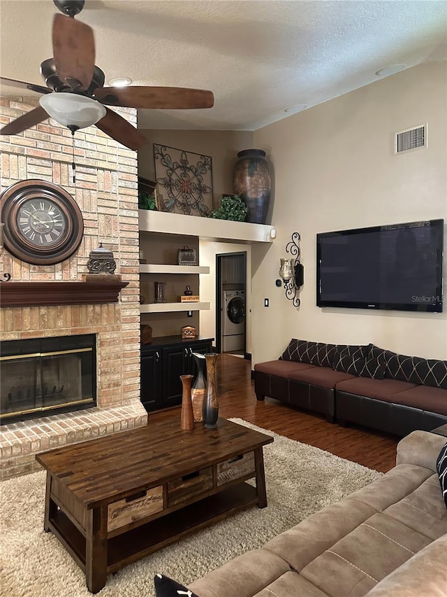 living area with visible vents, washer / dryer, wood finished floors, ceiling fan, and a textured ceiling