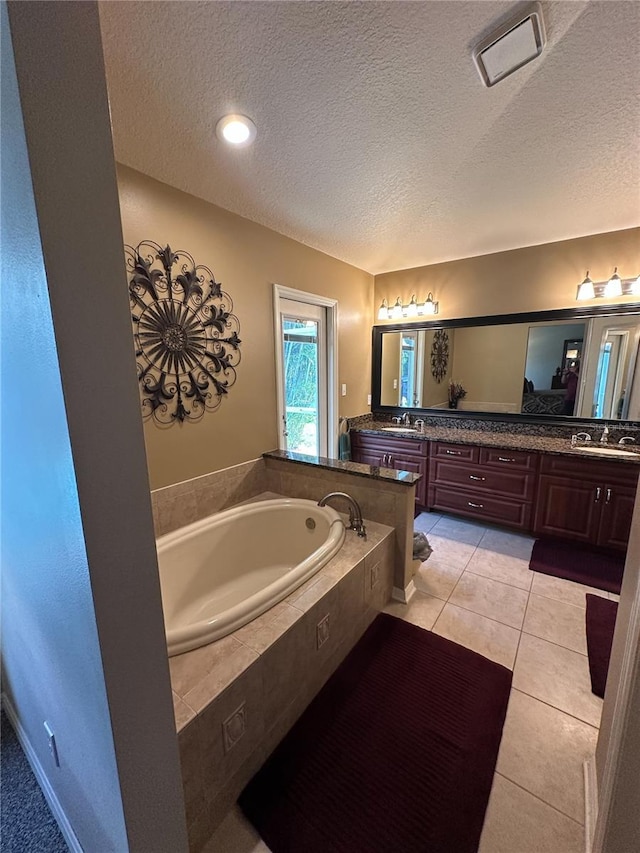 bathroom featuring a textured ceiling, tile patterned floors, vanity, and a bath