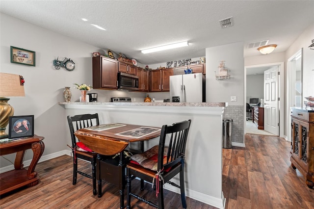 6745 Basswood Cir, Zephyrhills, FL 33542 - dining area with visible vents, a textured ceiling, and dark wood finished floors