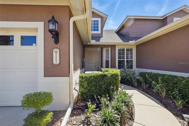 entrance to property with an attached garage and stucco siding
