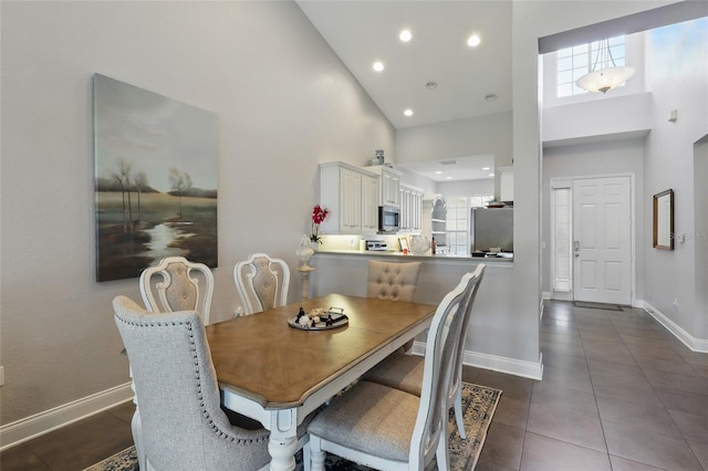 dining area with dark tile patterned flooring, a towering ceiling, baseboards, and recessed lighting