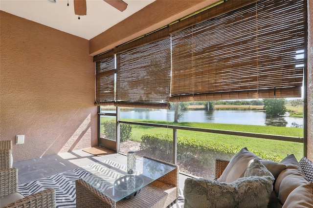 sunroom / solarium featuring ceiling fan and a water view