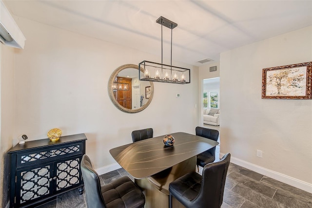 dining space featuring a chandelier, visible vents, baseboards, and stone finish flooring