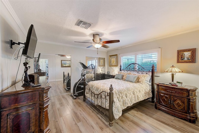 bedroom with a textured ceiling, crown molding, visible vents, ceiling fan, and light wood finished floors