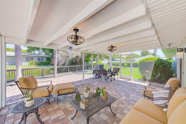 sunroom / solarium with beam ceiling, an outdoor living space, and a wealth of natural light