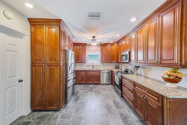 11035 Huron Rd, Saint Petersburg, FL 33708 - kitchen featuring appliances with stainless steel finishes, ceiling fan, light stone counters, backsplash, and recessed lighting