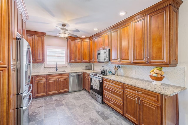 11035 Huron Rd, Saint Petersburg, FL 33708 - kitchen with stainless steel appliances, a sink, brown cabinetry, ceiling fan, and light stone countertops