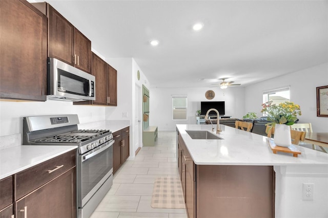 kitchen featuring a sink, ceiling fan, light countertops, an island with sink, and appliances with stainless steel finishes