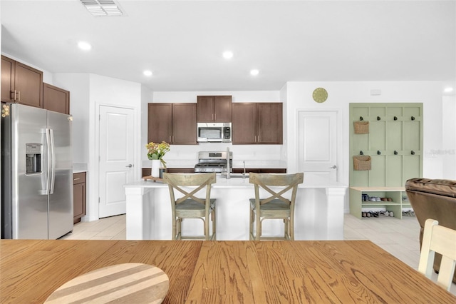 kitchen featuring dark brown cabinets, visible vents, appliances with stainless steel finishes, light countertops, and light tile patterned floors