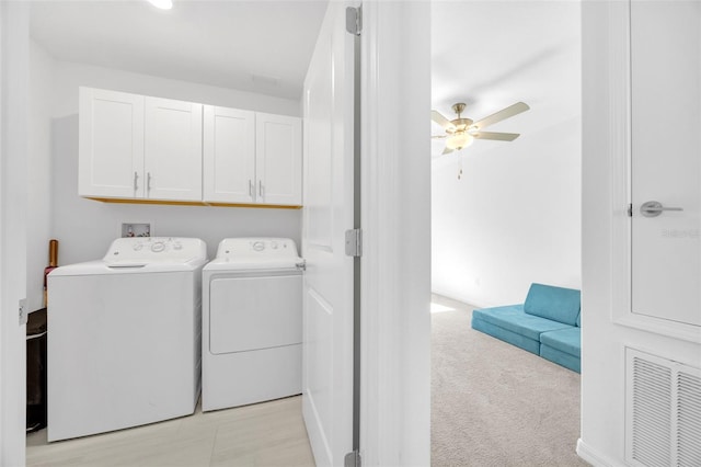 washroom featuring light carpet, visible vents, ceiling fan, cabinet space, and washer and dryer