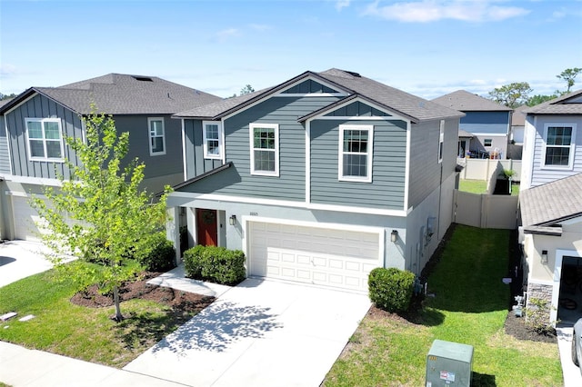 view of front of house featuring a front lawn, concrete driveway, fence, a garage, and board and batten siding