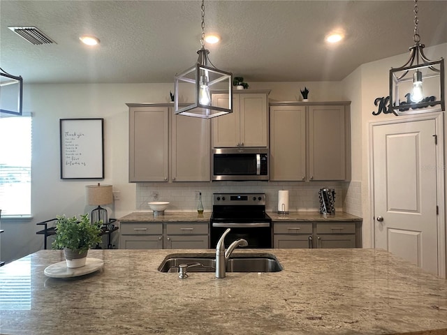 33034 Sand Creek Dr, Wesley Chapel, FL 33543 - kitchen featuring stainless steel microwave, electric stove, a sink, gray cabinets, and a textured ceiling