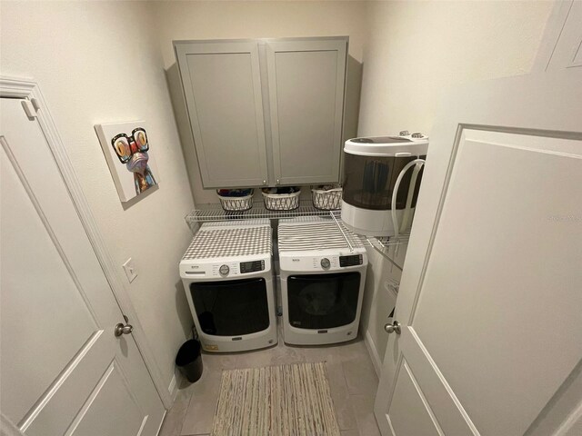 33034 Sand Creek Dr, Wesley Chapel, FL 33543 - laundry area featuring washing machine and dryer, cabinet space, and light tile patterned floors