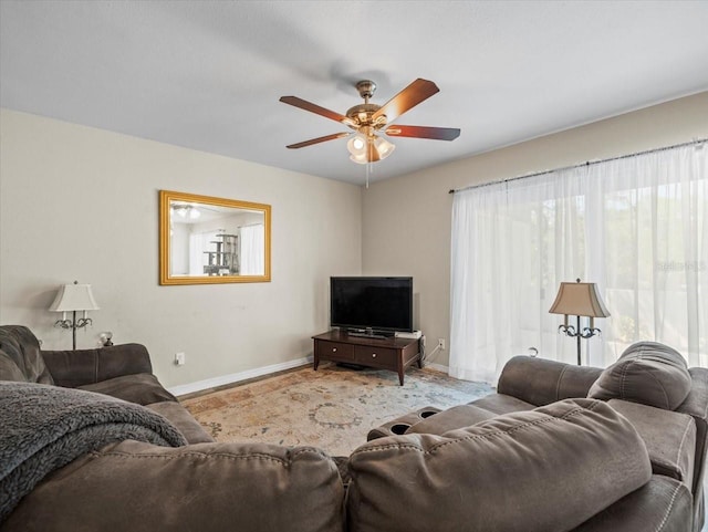 living room with baseboards and ceiling fan