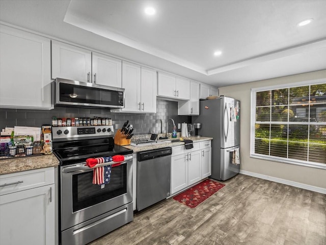 kitchen featuring tasteful backsplash, white cabinets, appliances with stainless steel finishes, and light wood finished floors
