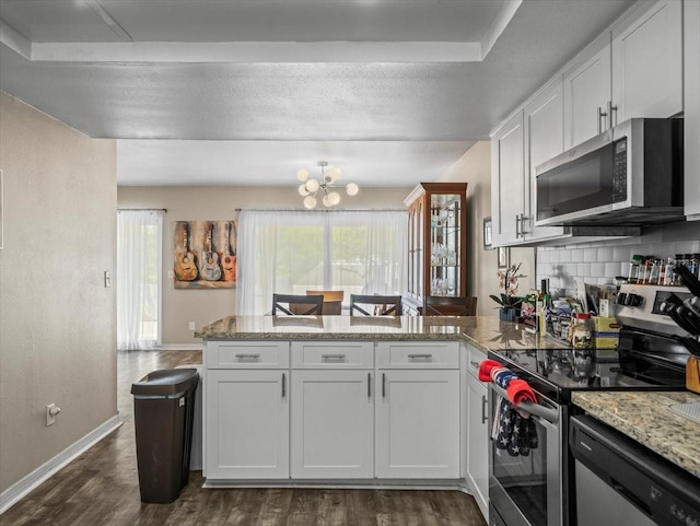 kitchen with a notable chandelier, baseboards, a peninsula, dark wood-type flooring, and appliances with stainless steel finishes