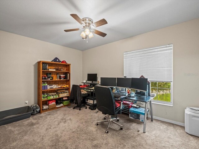 carpeted office space with baseboards and a ceiling fan