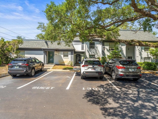 tri-level home featuring uncovered parking, stucco siding, and a shingled roof