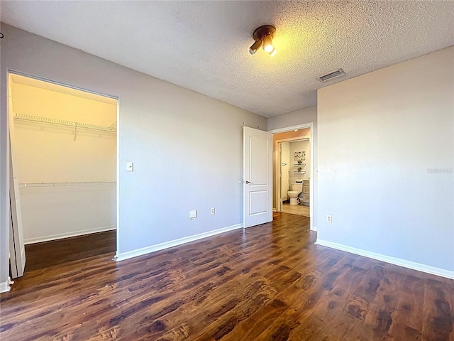 810 Island Walk Dr Unit 810, Tampa, FL 33602 - unfurnished bedroom featuring a closet, a walk in closet, dark wood finished floors, baseboards, and visible vents