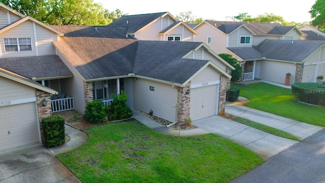 multi unit property featuring a front lawn, driveway, stone siding, a garage, and roof with shingles