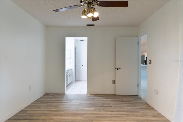 empty room featuring ceiling fan, a textured ceiling, visible vents, and light wood-type flooring