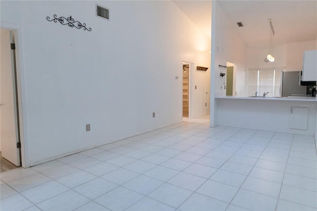 unfurnished living room with a towering ceiling, visible vents, and light tile patterned floors