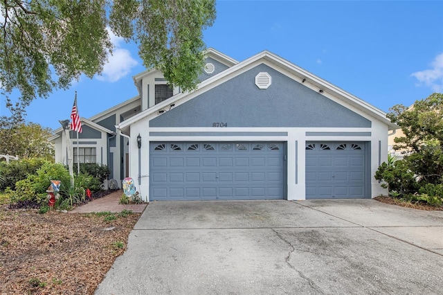 8704 Tarrington Pl, Tampa, FL 33635 - view of front facade with driveway, an attached garage, and stucco siding