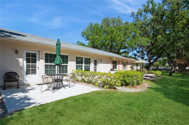 rear view of house featuring a patio, a yard, and stucco siding
