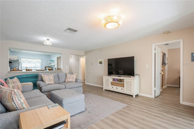 living area with wood finished floors, a textured ceiling, baseboards, and visible vents