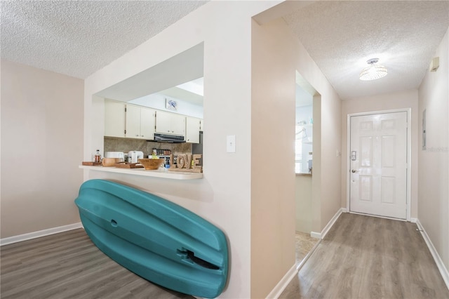 interior space featuring baseboards, a textured ceiling, and light wood-style flooring