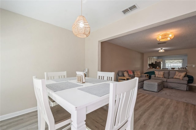dining area featuring baseboards, visible vents, and light wood-type flooring