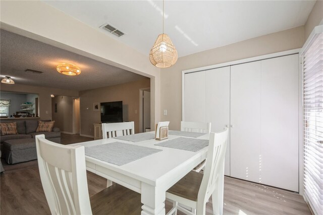 dining space with wood finished floors, visible vents, and plenty of natural light