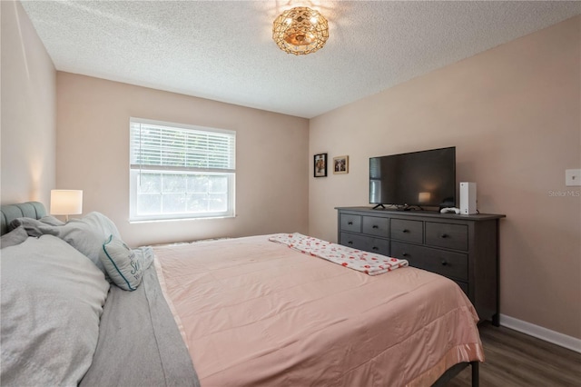 bedroom featuring baseboards, a textured ceiling, and dark wood finished floors