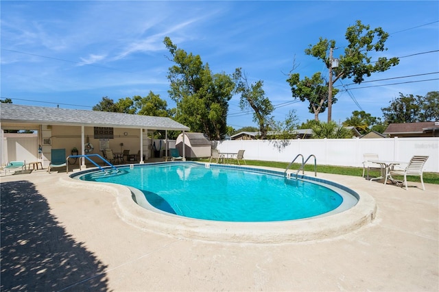 pool featuring an outdoor structure, fence, a patio area, and a storage unit