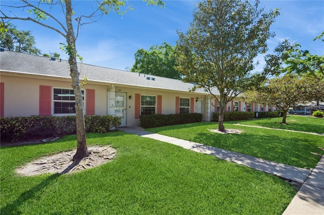 ranch-style home featuring stucco siding and a front lawn