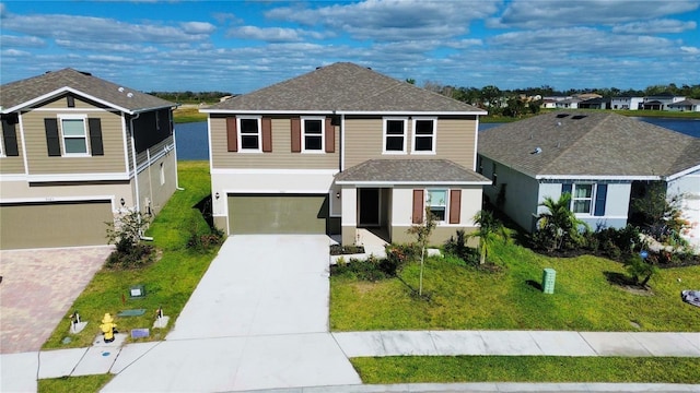 traditional-style home with concrete driveway, an attached garage, a shingled roof, a front yard, and stucco siding