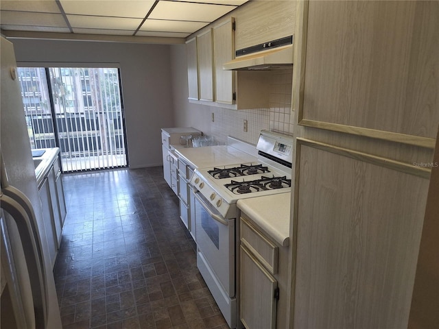 kitchen featuring tasteful backsplash, refrigerator, light countertops, gas range gas stove, and under cabinet range hood