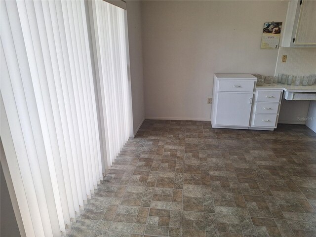interior space with baseboards and brick patterned floor