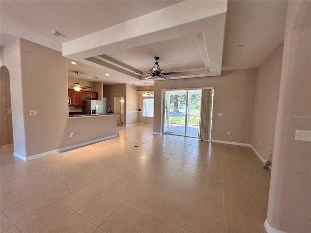 1201 Ventana Dr, Sun City Center, FL 33573 - unfurnished living room with ceiling fan, light tile patterned floors, arched walkways, a raised ceiling, and baseboards