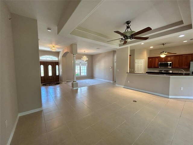 1201 Ventana Dr, Sun City Center, FL 33573 - interior space featuring a tray ceiling, arched walkways, light tile patterned floors, and ceiling fan