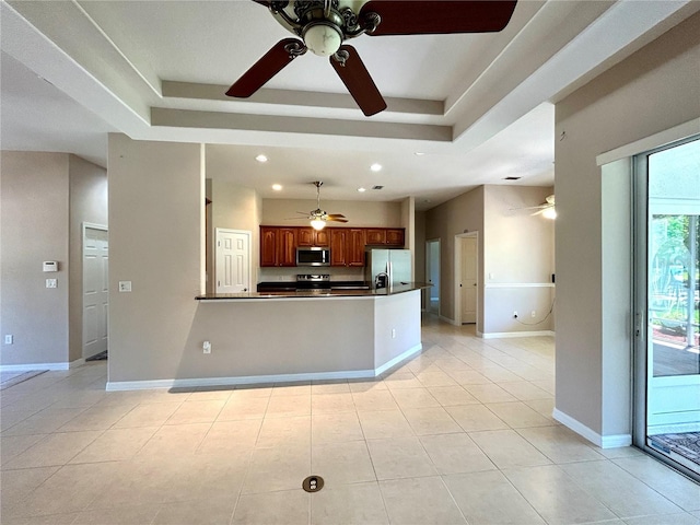 1201 Ventana Dr, Sun City Center, FL 33573 - kitchen with ceiling fan, dark countertops, appliances with stainless steel finishes, a peninsula, and a tray ceiling