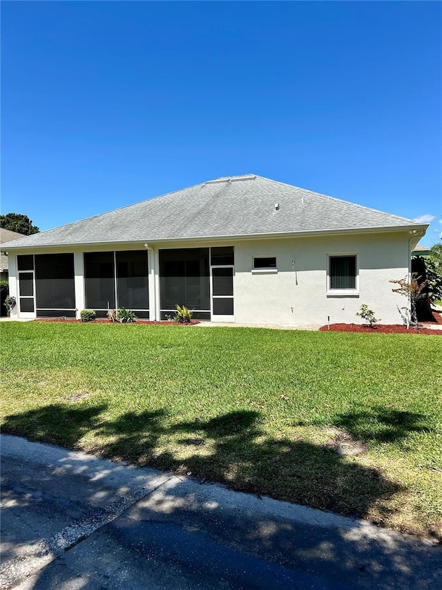 1201 Ventana Dr, Sun City Center, FL 33573 - back of house with a sunroom, a shingled roof, stucco siding, and a lawn