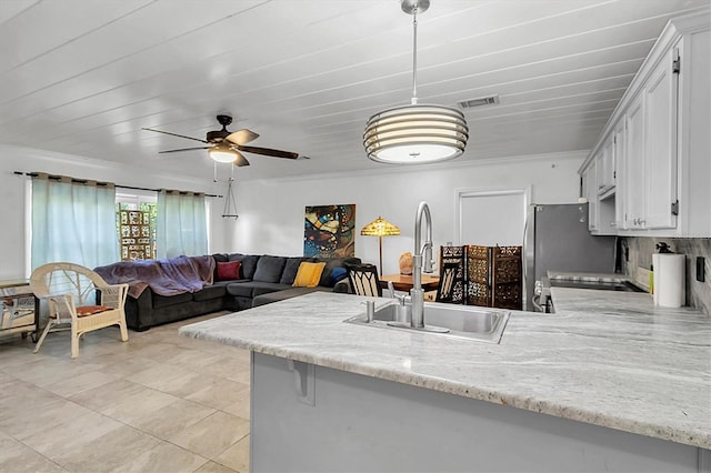 9520 Indale Dr, New Port Richey, FL 34654 - kitchen with white cabinets, visible vents, a ceiling fan, a sink, and a peninsula