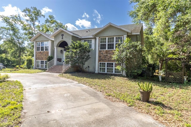 9520 Indale Dr, New Port Richey, FL 34654 - bi-level home featuring a front yard, stone siding, concrete driveway, and stucco siding